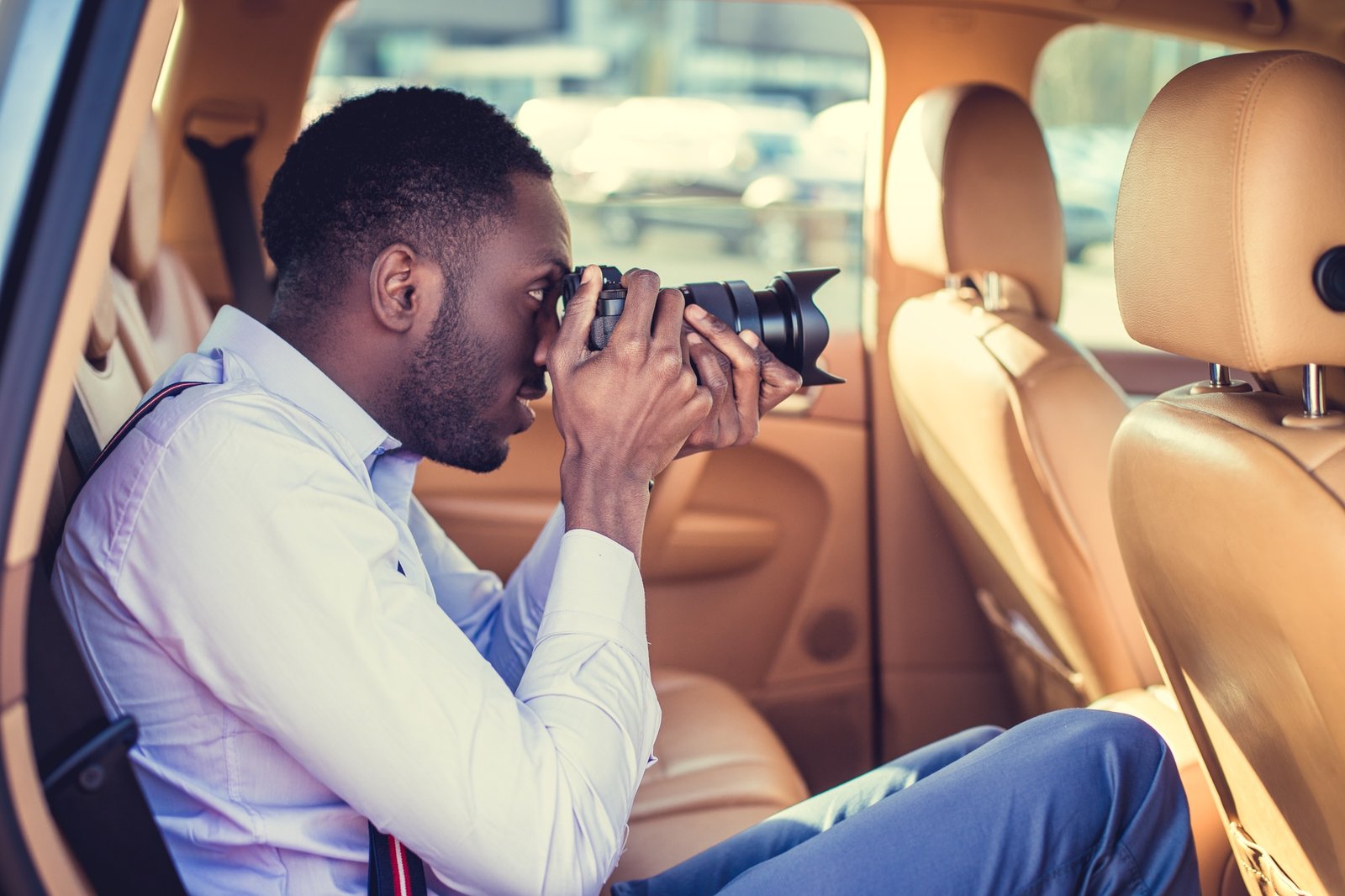 A black man using dslr camera in a car.